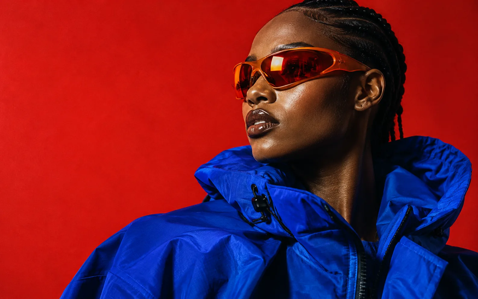 Editorial portrait in cobalt blue against a vermilion backdrop